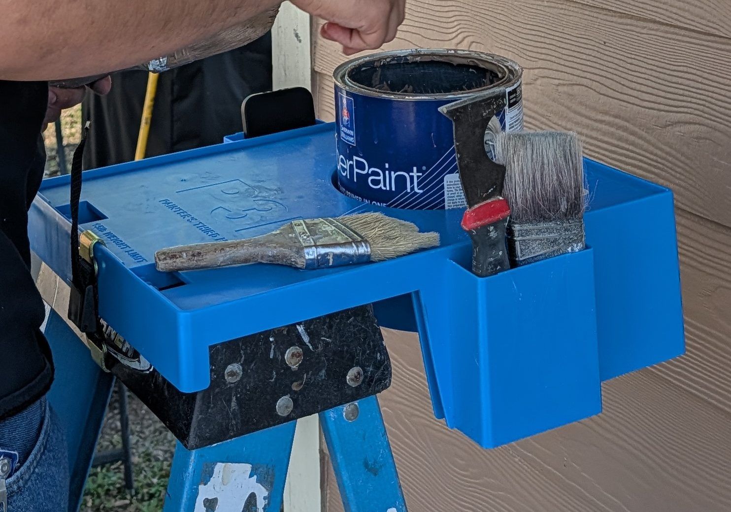 The P3Hpro on a job: paint can in the well, brushes in the side pocket, a brush on the deck and the cam-buckle strap around the ladder's top cap