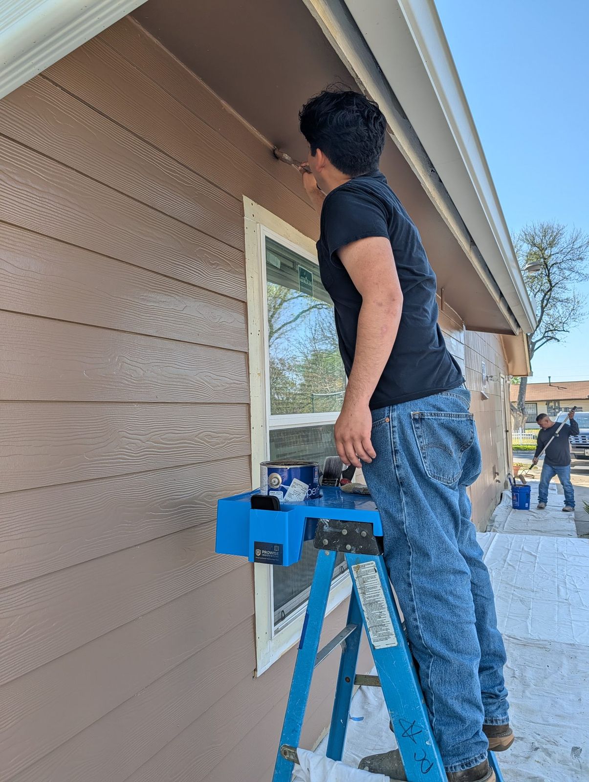 Painter reaching up to an eave while the P3Hpro holds his paint can on the ladder