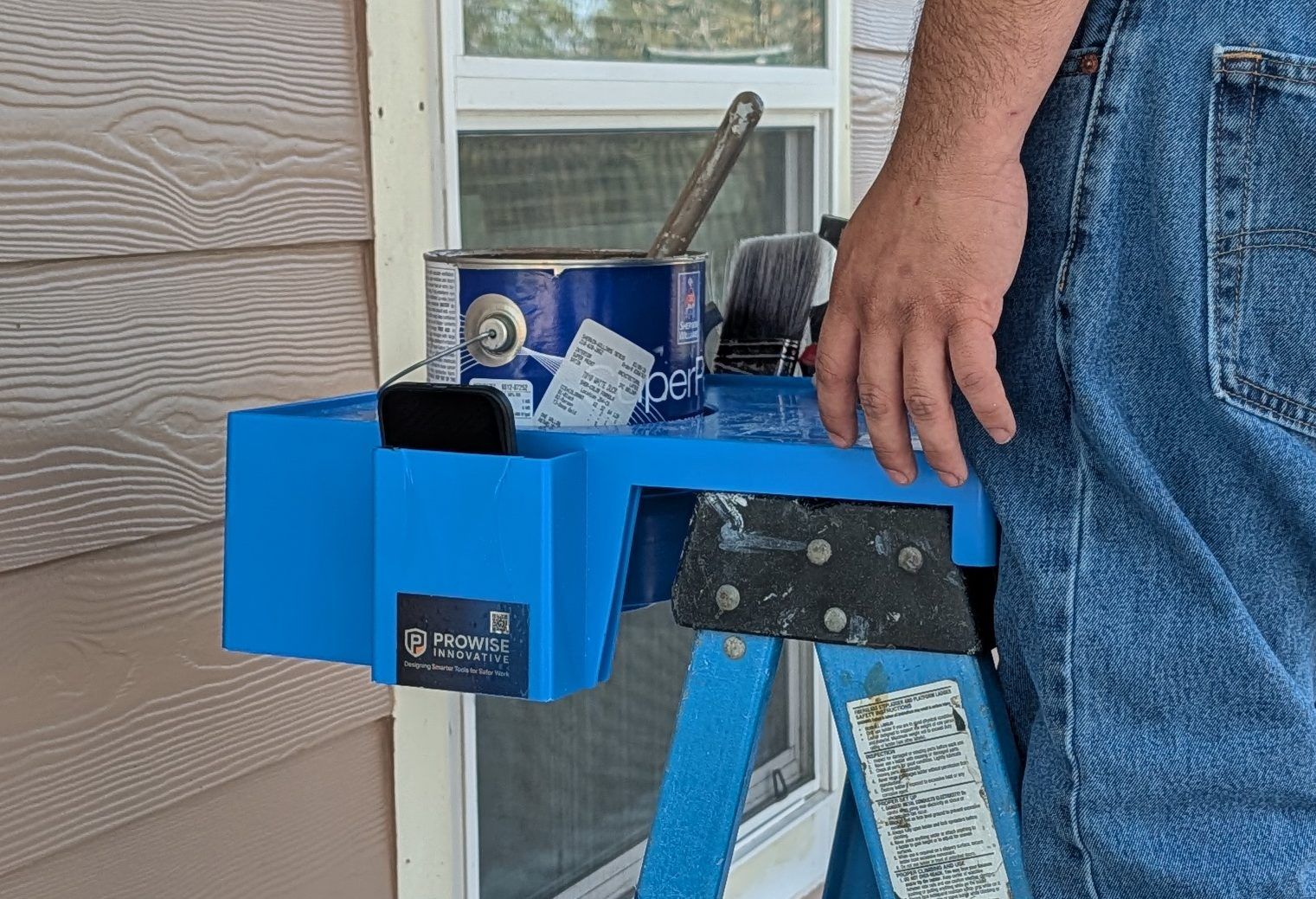 ProWise P3Hpro Project Platform in blue on a step ladder, with a paint can, brushes, a phone and the ProWise badge on the pocket